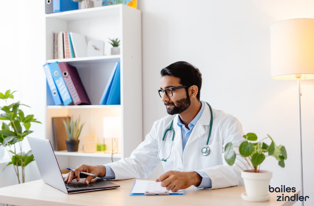 Doctor reviewing a custom medical website on a laptop, representing Bailes + Zindler’s HIPAA-compliant web design services for healthcare providers.