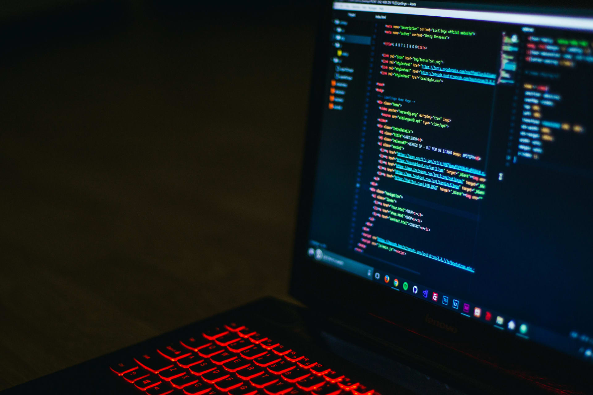 Laptop with red backlit keys with a coding editor on screen with code