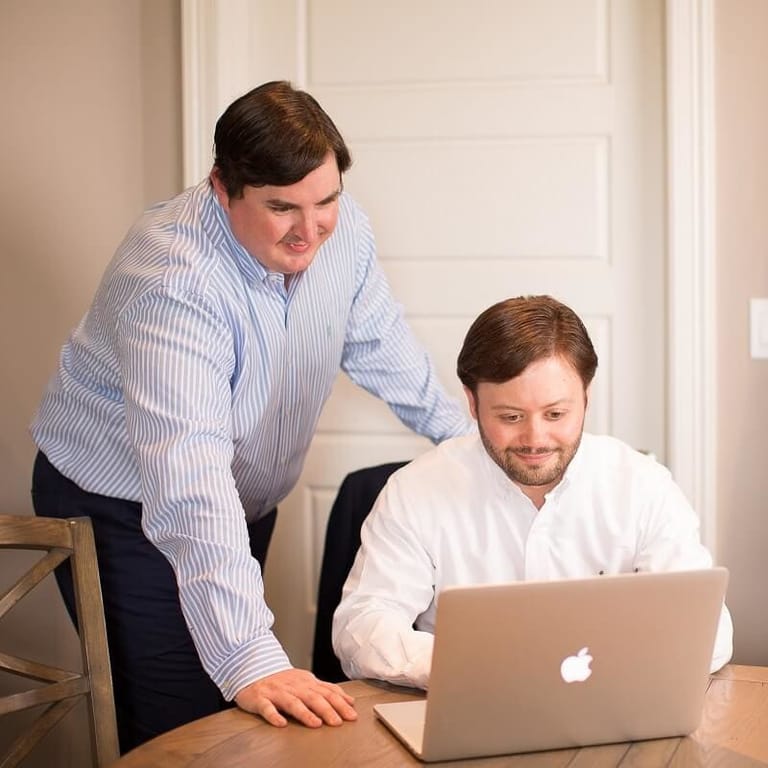Ryan Bailes and Seth Zindler looking at a laptop while working.