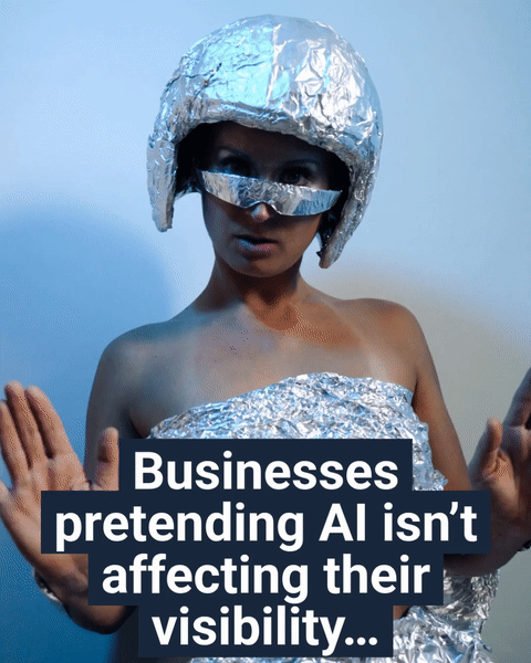 Person wearing a helmet and outfit made of aluminum foil with a foil visor over their eyes, holding both hands up as the caption reads “Businesses pretending AI isnt affecting their visibility,” poking fun at brands acting like AI search is something they can ignore.